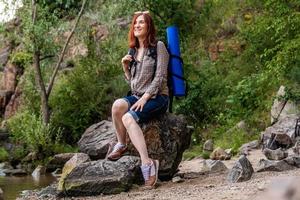 mujer turista con una mochila un fondo de montañas y ríos foto