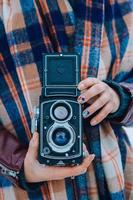 mujer joven sosteniendo en las manos vieja cámara vintage. fotógrafa foto