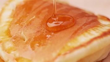 Hands pouring honey onto tasty pancakes. video