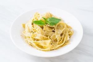 Pasta fettuccine al pesto con queso parmesano encima - estilo de comida italiana foto