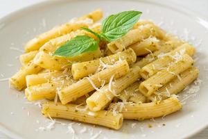 pasta al pesto rigatoni con queso parmesano - comida italiana y estilo vegetariano foto