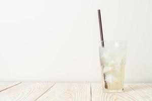 agua de coco o jugo de coco en vaso con cubito de hielo foto