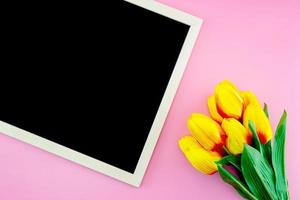 Yellow tulip flower and chalkboard, blackboard on the pink background photo