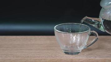 cámara lenta de agua caliente se vertió en un vaso servido en la mesa