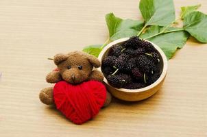 Close up of Teddy dol with red heart and Mulberry fruits photo