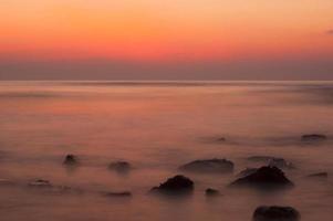 Soft waves on a rocky beach in the evening photo