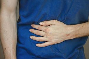 A man holding his stomach. Close up. photo