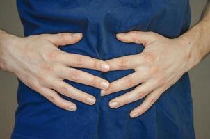 A man holding his stomach. Close up. photo