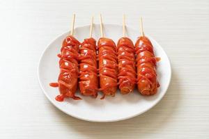 Fried sausage skewer with ketchup on white plate photo