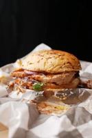 beef burger on a chopping board against black background photo