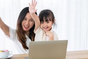 Madre asiática jugando juegos de computadora con el niño en la sala de estar foto