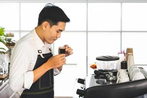 joven barista asiático disfruta del olor a café caliente en la cafetería foto