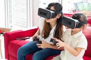 asian mother playing virtual reality game with child in living room