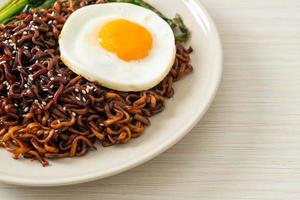 fideos instantáneos secos coreanos picantes con salsa negra casera con huevo frito y kimchi foto