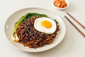 fideos instantáneos secos coreanos picantes con salsa negra casera con huevo frito y kimchi foto