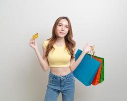 Retrato hermosa mujer asiática sosteniendo una bolsa de compras y una tarjeta de crédito sobre fondo blanco. foto
