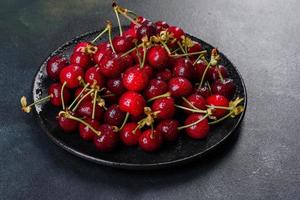 Frescas y deliciosas bayas de cerezo rojo brillante rasgadas en el jardín de verano foto