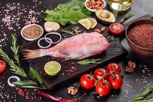 Raw fillet of red sea perch prepared for baking with spices and herbs photo