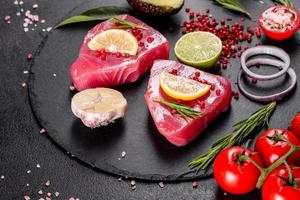 Fresh tuna fillet steaks with spices and herbs on a black background photo