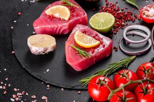 Fresh tuna fillet steaks with spices and herbs on a black background photo