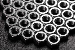 Metal steel nuts laid in composition on a dark table photo