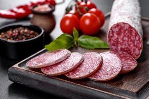 Spanish dried sausage salami on a dark concrete background photo