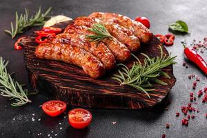 Grilled sausages with vegetables and spices on black background photo