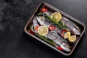 Raw trout lie on a black stone chopping board on a dark concrete table photo