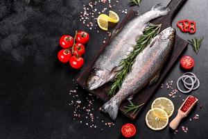 Raw trout lie on a black stone chopping board on a dark concrete table photo