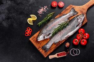 Raw trout lie on a black stone chopping board on a dark concrete table photo