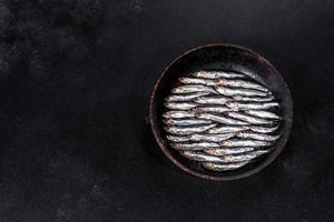 Varios pescados de anchoas saladas sobre una mesa de hormigón oscuro