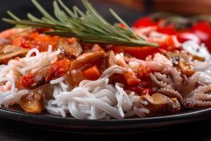 Tasty rice noodles with tomato, red pepper, mushrooms and seafood photo
