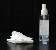 Hand sanitizer with tissue isolated on black background photo