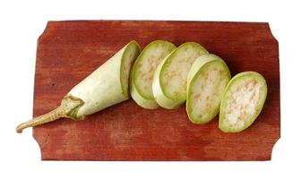 Green eggplant on a wooden cutting board isolated on a white photo