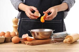 Woman hands to separate egg white and yolks with egg shells photo