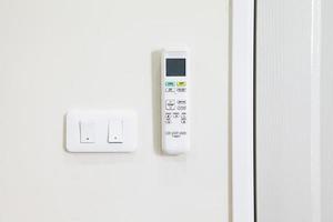 control remoto para aire acondicionado e interruptor de encendido colgado en la pared foto