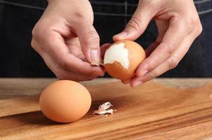 Chef pelando huevos duros en la tabla de cortar en la cocina foto