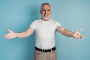 Elegant senior man over isolated blue background, looking at camera photo