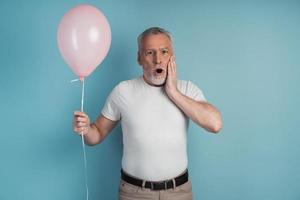 Surprised senior man holding a pink ball in his hand photo