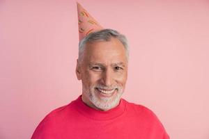 hombre alegre y sonriente con un sombrero festivo sobre un fondo rosa. foto