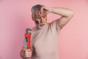 Tired man with a wrench in his hands grabbed his head photo