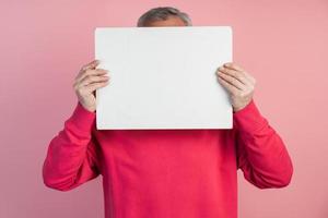 Man covers his face with a white sheet of paper photo