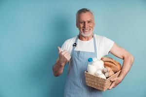 Smiling man with gray hair and a beard holds a basket of food photo