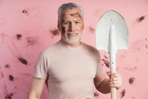 Hombre positivo con una pala sobre un fondo de una pared rosada sucia foto