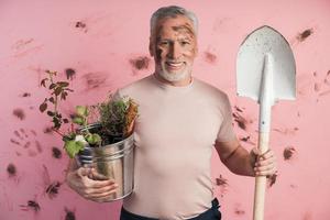 hombre mayor, jardinero con una pala y un balde en sus manos foto