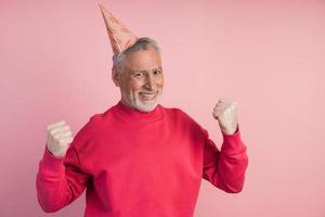 Confident senior man in a holiday hat rejoices in victory photo