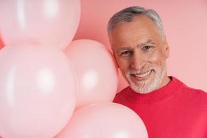 Senior man with gray hair and beard and pink balloons photo