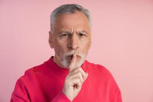 Senior man shows gesture to be quiet photo