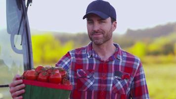 Portrait of farmer sitting on tractor with basket of tomatoes video