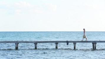 Woman walks down pier at tropical resort video